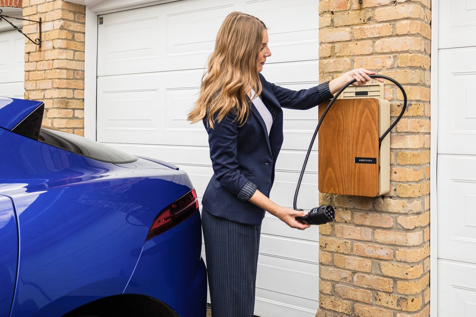 A driver charging a home EV with a wall-mounted charger