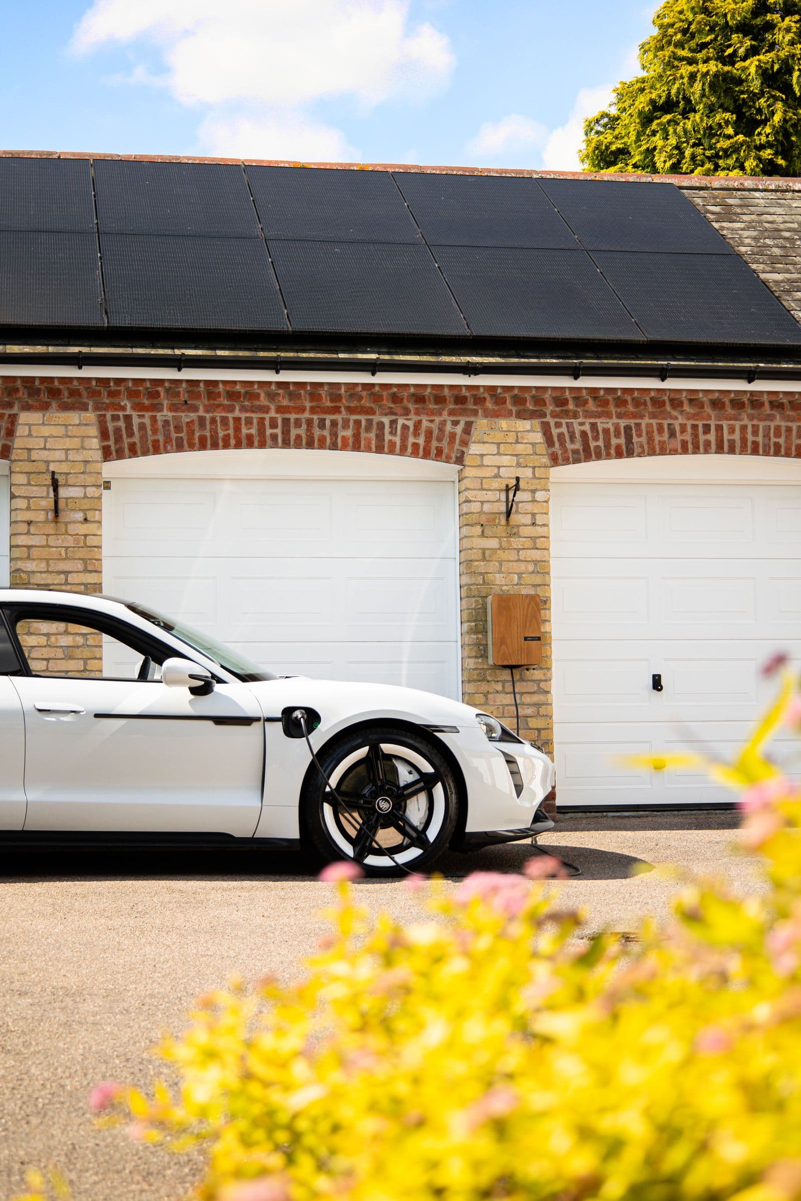 An electric car at a home with solar panels on the roof